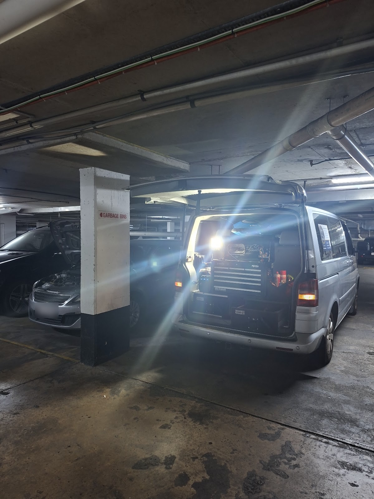 The van with its lights on in an underground apartment car park