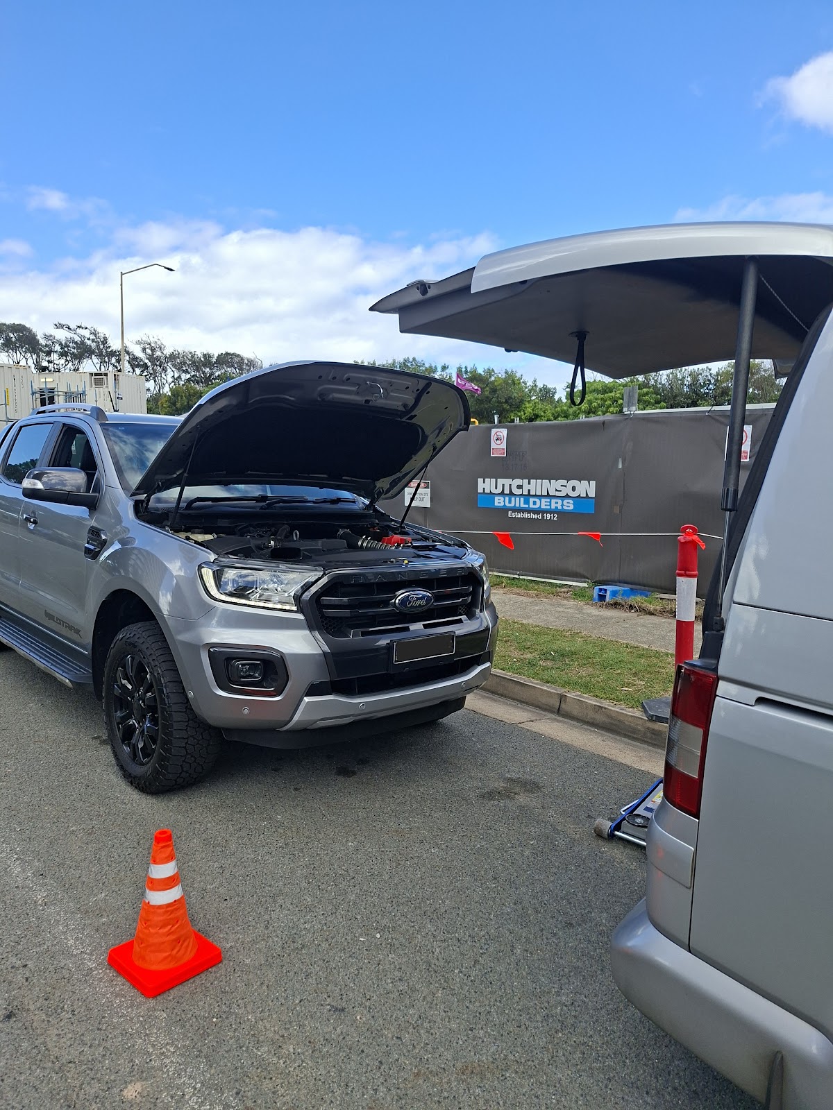 Grey Ford Ranger with the bonnet open on a roadside job, the service van alongside