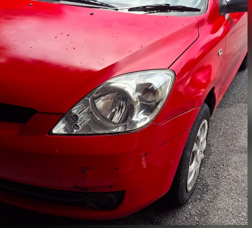 Front corner of a red hatchback with a clear headlight
